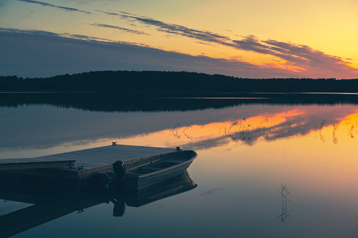 A motorboat at a jetty at sunset on a calm evening in Kimito island, Finland.