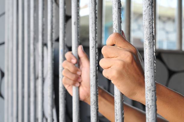 istock someone's hand holding iron bars in prison 2002239663