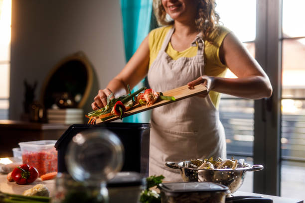 istock Woman adding veggie scraps into a composting bin after preparing food 2002244959