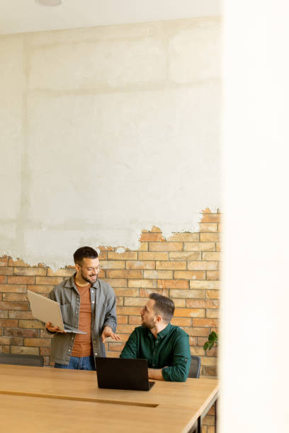 istock Collaboration in Motion, Professionals Working Together in a Modern Brick-Walled Office 2002271427