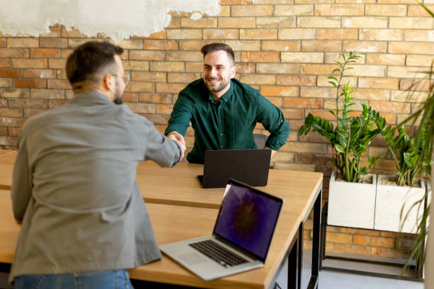 istock Cordial Handshake Over Laptops in a Brick-Walled Office Space 2002277263