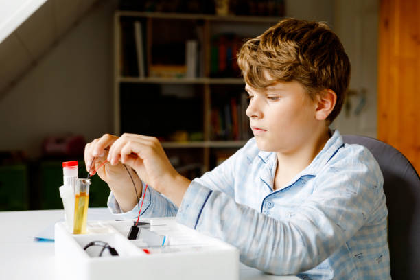 Preteen kid boy doing electric physical experiment as homework at home. Child study electricity. Education. Kids learning physics