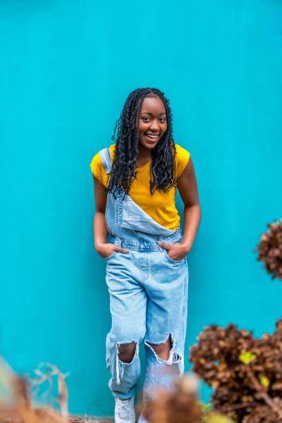 istock Cool young african woman leaning in a blue background wall 2002342239