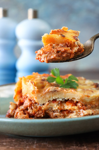 Stock photo showing close-up view of freshly cooked lasagne pasta recipe that has been baked and topped with a white sauce (bechamel sauce), and a mixture of grated parmesan and melted Grana Padano cheese. The lasagne has been made with sheets of egg pasta, laid in alternative layers with a rich, tasty bolognese sauce.