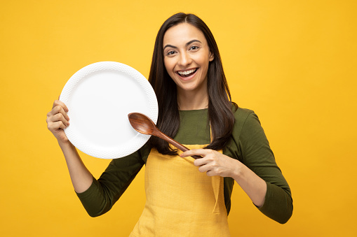 Photo of pretty positive young chef in yellow apron isolated on yellow background