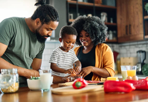 child family kitchen food boy son mother father breakfast preparing egg morning healthy diet eating home black african american father cooking parent cute meal kid Portrait of mother, father and son preparing and eating breakfast in the kitchen at home family dinners and cooking stock pictures, royalty-free photos & images