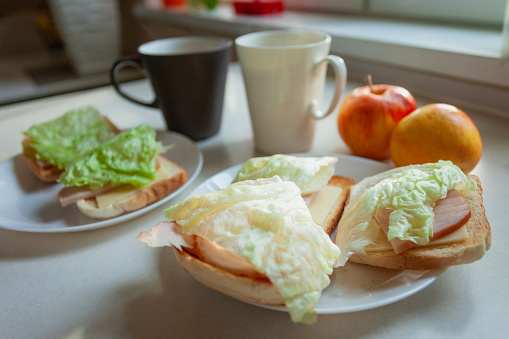 Sandwiches with toast, cold cuts and salad for breakfast with two apples