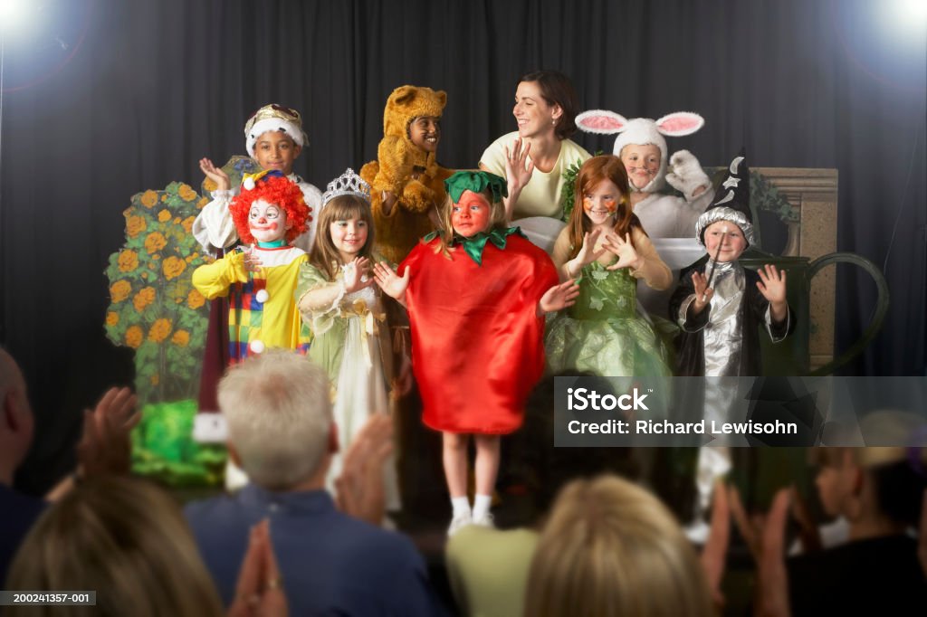 Kinder (4 bis 9) tragen Kostüme und Lehrer winken auf der Bühne - Lizenzfrei Aufführung Stock-Foto