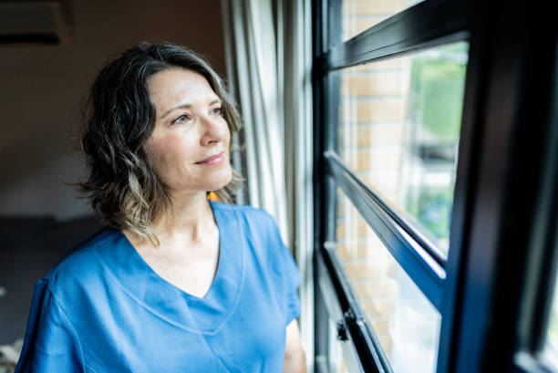 istock Mature home caregiver looking through the window at home 2002506671