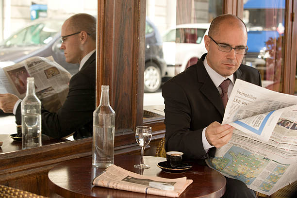 empresário maduro, sentado no lado de fora de café, ler jornal - newspaper reading broadsheet paper - fotografias e filmes do acervo