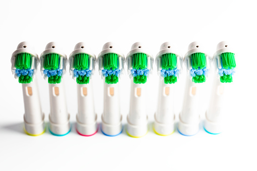 Close up macro color image depicting new electric toothbrush heads in a row on a white background.
