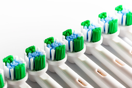 Close up macro color image depicting new electric toothbrush heads in a row on a white background.