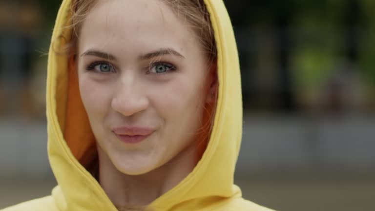 Girl teenager in hood puts on sunglasses smiling closeup