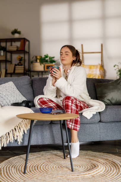 istock Young woman having morning coffee on the sofa with her breakfast cereal 2002535251