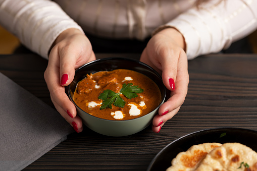 Young woman eating butter chicken curry and naan bread