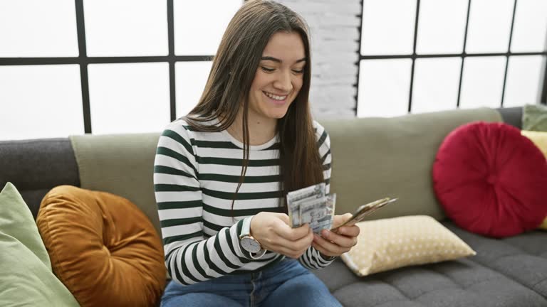 Young woman counting peruvian soles in a cozy living room setting