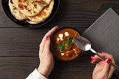 Young woman eating curry and naan bread