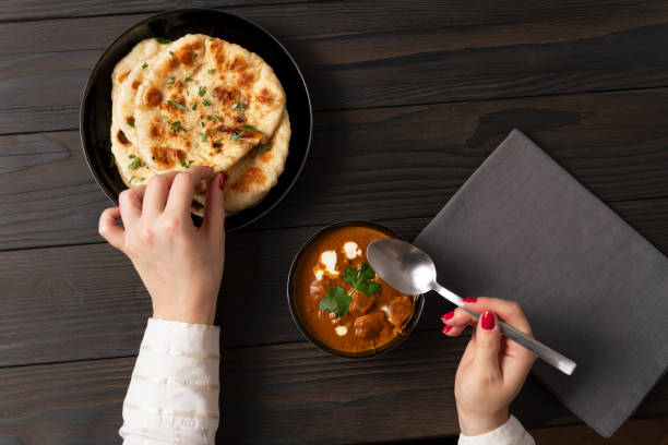 istock Young woman eating curry and naan bread 2002539292