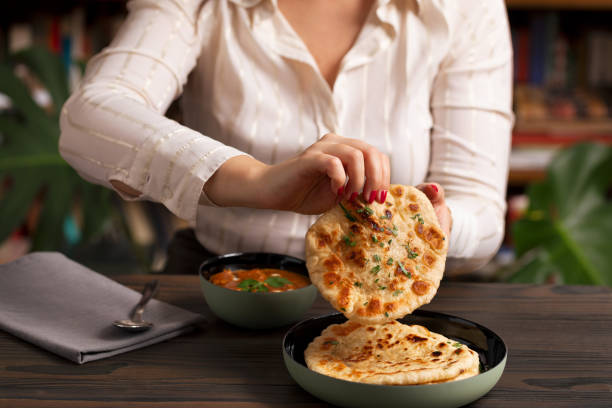 istock Young woman eating curry and naan bread 2002541722