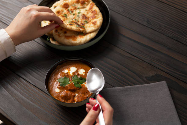 istock Young woman eating curry and naan bread 2002542062