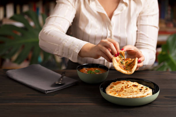 istock Young woman eating curry and naan bread 2002543718