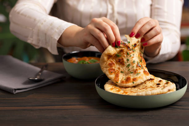 istock Young woman eating curry and naan bread 2002545869