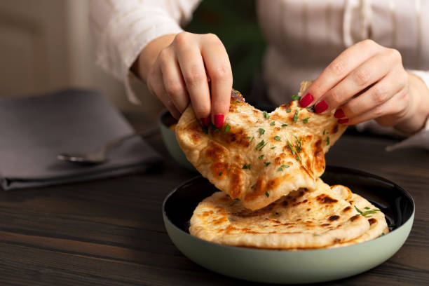 istock Young woman eating curry and naan bread 2002545873