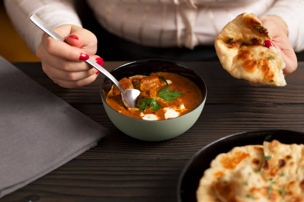 istock Young woman eating curry and naan bread 2002550314