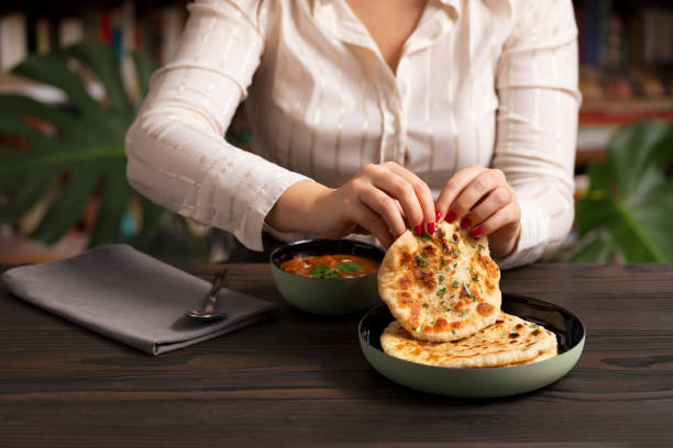 istock Young woman eating curry and naan bread 2002552631