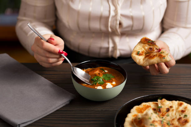 istock Young woman eating curry and naan bread 2002552633