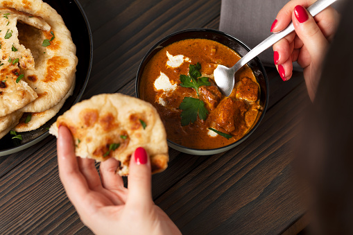 Young woman eating butter chicken curry and naan bread