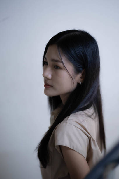 A woman wearing a mysterious path turns away from the camera. Make her look mysterious With the color tone of the picture looking dark