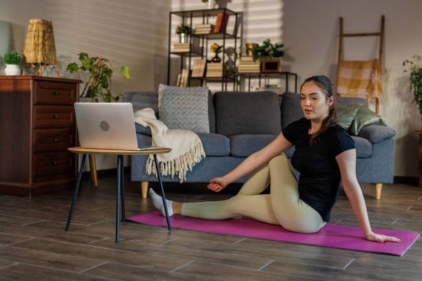 istock Young woman sitting on exercise mat and stretching 2002558824