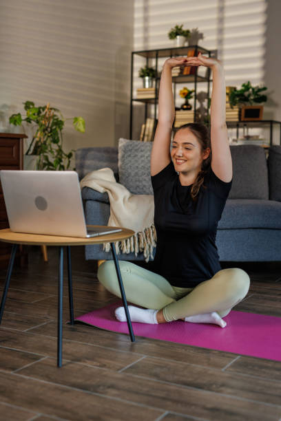 istock Young woman sitting on exercise mat and stretching 2002558857
