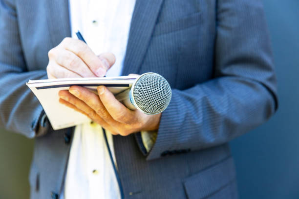 istock Journalist, correspondent or reporter at media event, holding microphone, writing notes. Broadcast journalism concept. 2002577283