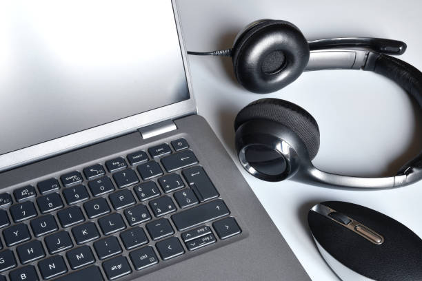 Working place  with laptop, headphones and computer mouse on white office desk.