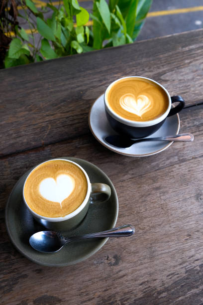 istock Two cups of coffee on black rustic background with beautiful latte art 2002609023