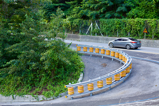 Gangneung City, South Korea - July 29th, 2019: A challenging steep road switchback between Simgok Port and Jeongdongjin, with a car navigating the sharp curve and steep incline, showcasing the rugged terrain of the coastal region.