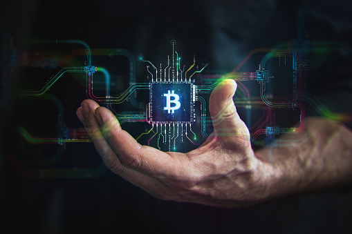 Crypto Currency in your hand. Male hand holding futuristic BTC chip in the center and circuit board with vibrant data transfers, representing evolving crypto payment technology of the future.