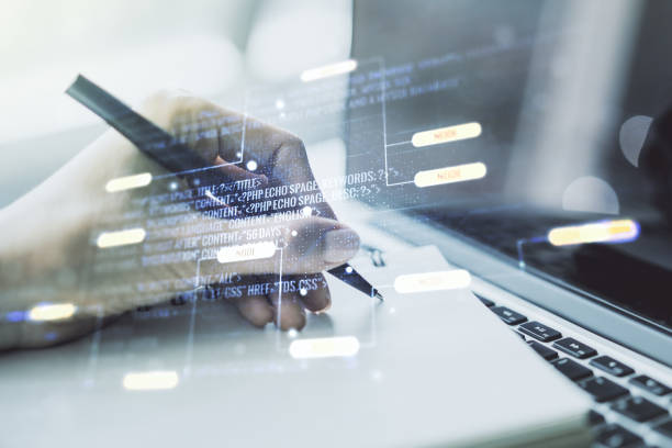 istock Multi exposure of abstract software development hologram and hand writing in notebook on background with laptop, research and analytics concept 2002640602