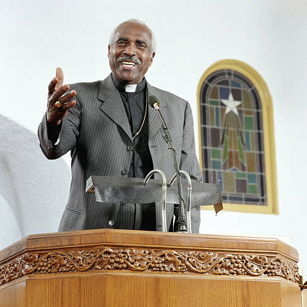 sacerdote senior dando sermon, sonriendo, vista de ángulo bajo - preacher fotografías e imágenes de stock