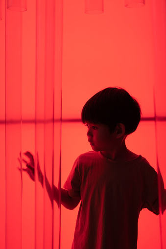 Little Asian boy, dark red background.