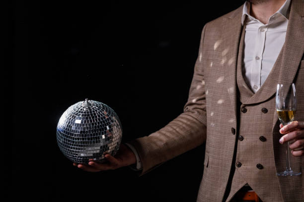 istock Charming man in a suit holding a disco ball in his hand 2002724693