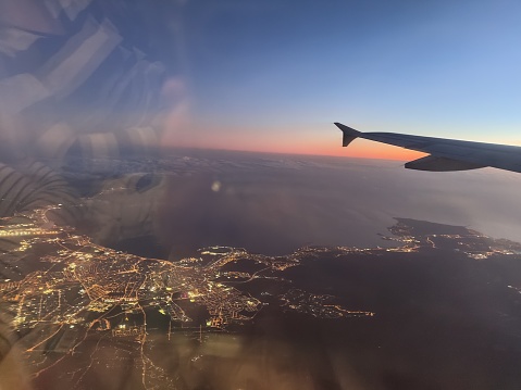 Shot of city streets and bay of Palma de Mallorca from a plane at sunset including wing