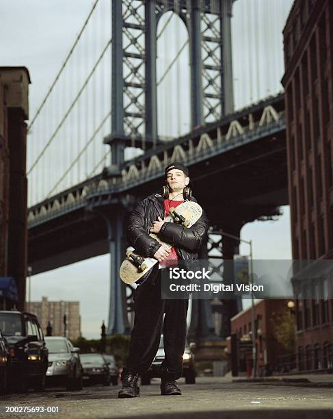 Jovem Segurando Skate Retrato Ponte De Manhattan Na Parte De Trás - Fotografias de stock e mais imagens de Skate - Atividade Recreativa