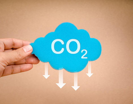 Reduce CO2 emissions, limit climate change, global warming, net zero carbon dioxide footprint reduction, decarbonize concepts. Reduce CO2, icon on cloud sponge hold by hand on eco brown background.
