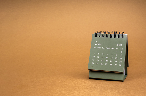 Green of March 2024 desk calendar for the organizer to plan and reminder isolated on brown craft paper background with copy space, minimal style. Small table calendar with the page of third month.