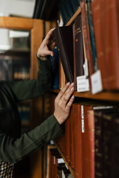 istock Beautiful young woman taking book from bookshelf in library 2002794447