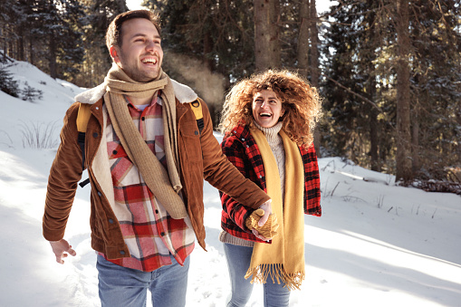 Young casually clothed couple enjoying winter day together in mountain