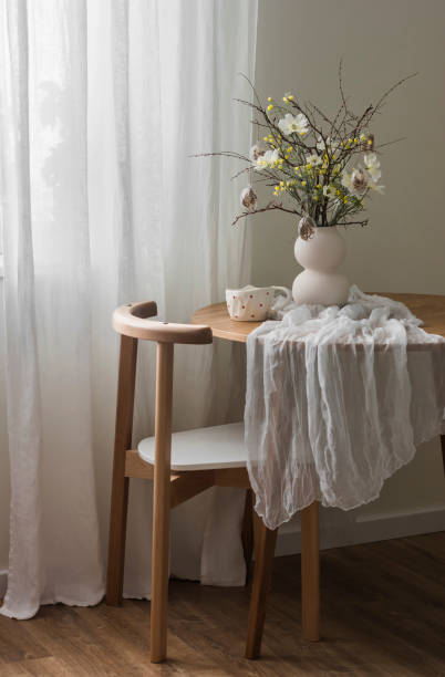 istock Easter bouquet with flowers, dry branches, glass eggs on a wooden round table with a white tablecloth in the living room 2002804980